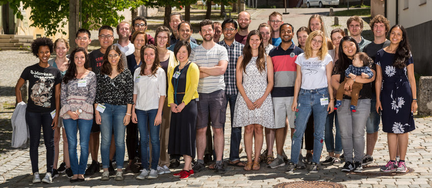 Group photo of 30 doctoral students, taken outdoors in summer.